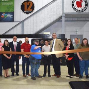 A group of people stood behind a ribbon inside a hall