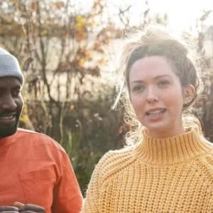 A person in a yellow-knit jumper talking to a group of people