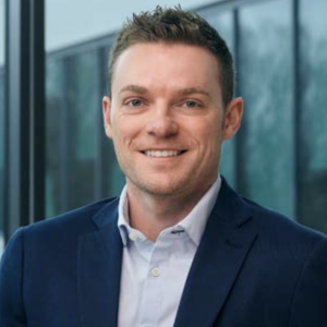 Headshot of a person smiling against a window