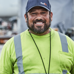 Headshot of a person wearing a FedEx hat