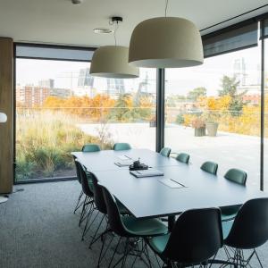 Conference room in modern office building with floor to ceiling windows that look out onto a green space