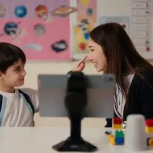 A child pointing to a teacher's nose