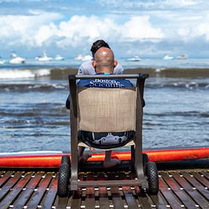 Person in wheelchair on the beach, looking out at the ocean