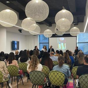 A room full of seated people, three speakers at the front.