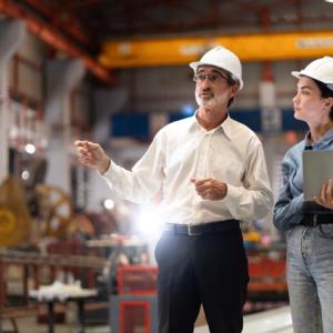 Two people wearing hard hats speaking in a workshop