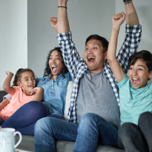 Family seated on a couch watching TV and cheering!