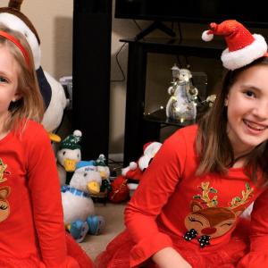 Young girls shown wearing reindeer pajamas with the Aflac Holiday Duck in the background.