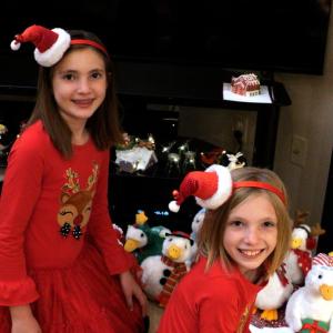 Two girls shown wearing Santa hats with the Aflac Holiday Ducks.