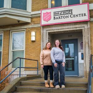 Picture of Amanda Henriott and Layknn Davidson standing next to eachother in front of The Salvation Army, block of Hope Barton Center entrace.