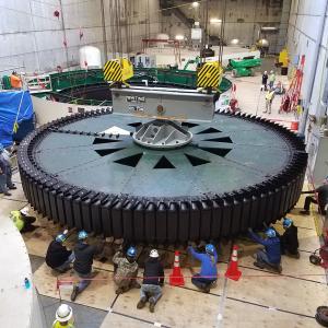workers surround a large rotor inside a huge complex