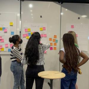 students stand in front of white boards covered in bright sticky notes
