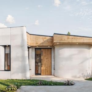 Rendering of a 3D-printed home which is white with a brown roof.