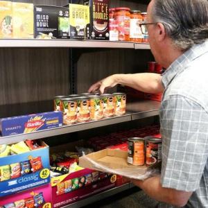 Person stocking cans in food pantry