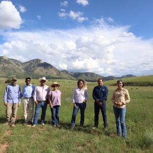 Boomitra staff and stand in a grasslands field with local ranchers 