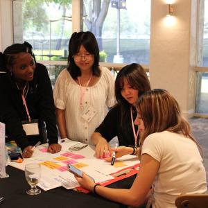 Participants collaborate at a table, writing ideas on a large poster board during an interactive workshop session.