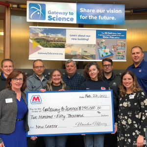 Group of 9 people stand in front of a "gateway o science" display holding a large check from Marathon petroleum 