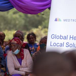 group of people sitting at presentation. A board reads, "Medtronic Labs: Global Health, Local Solutions"