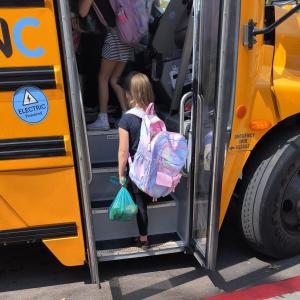 Child boarding electric bus with produce