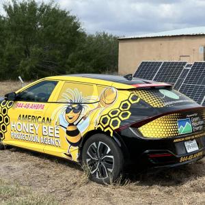 Yellow and black KIA parked in front of ground-mounted solar array 