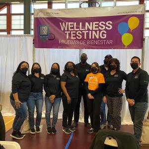 group of people under a banner saying "wellness testing"