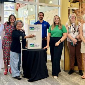 Members of Cancer Bridges, Connected Energy Solar, and Green Mountain Energy Sun Club "Flipping the Switch" with a life-size light switch.