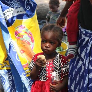 A young girl in the Kaande Camp eats corn. She and her family have little to eat this month.