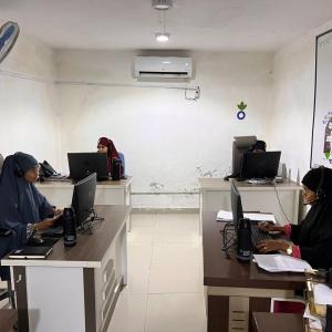 Three women work at desks in a white room in the call center. 