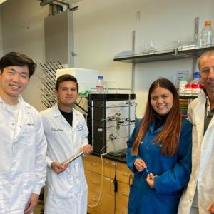 Three students in a lab with a teacher.