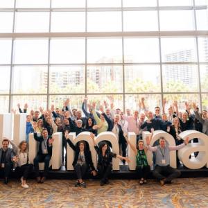 Illumina employees seated in front of the Illumina logo in the corporate headquarters.