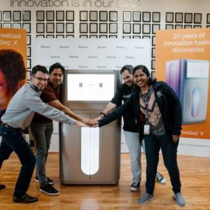 In front of the patent wall at Illumina's San Diego headquarters, employees gather around the NovaSeq X Plus.