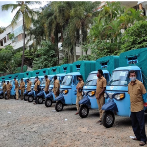 A row of identical small vehicles with drivers standing to the side.