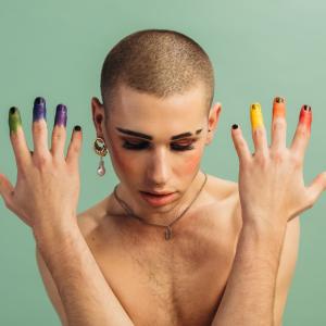 Person shown with rainbow colored fingers.