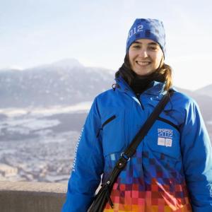 Smiling woman wearing hat and jacket reading "Innsbruck 2012"
