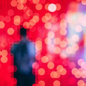 unfocused silhouette of a person in front of a field of pixelated red and blue lights