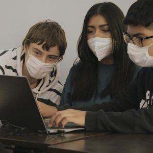 Three students using a laptop