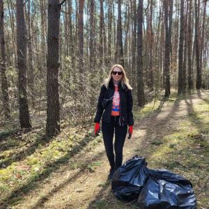 person standing near the woods with two large garbage bags