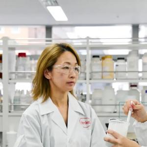Three people in a lab environment looking at a substance.