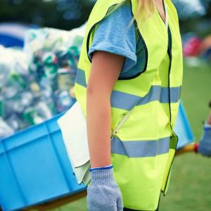 two people wearing reflective vests carrying carts full of recycling