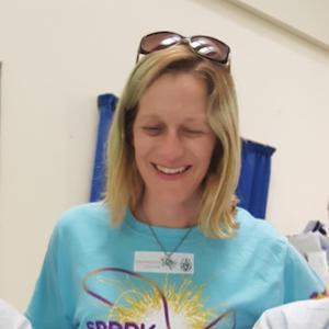 A woman in a blue SPARK™ MilliporeSigma t-shirt engages with students.
