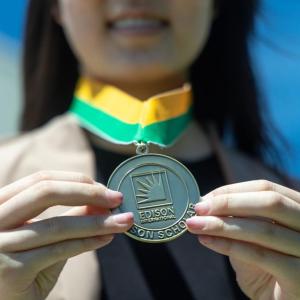 Edison Scholar Janna Lee holding out her medal