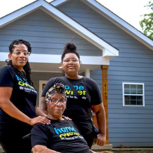 Janetta and two family members outside their new home.