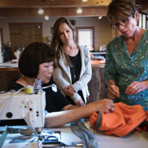 3 people look at a garment being put together