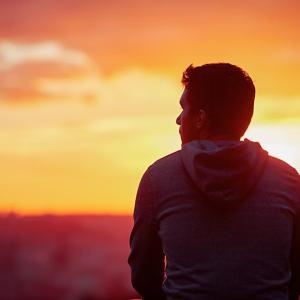 A person looking to the distance, a sunset over the horizon.