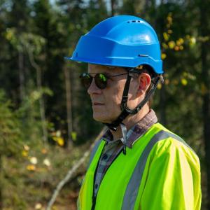 John Mulcahy in hard hat and high-vis clothing standing in a forested area.