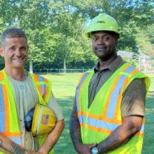 Jonathan Harmon and Eric Adams, both outside wearing safety vests