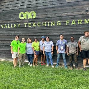 Group of volunteers stood outside of a 'Jone Valley teaching farm' building