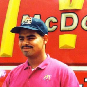 A young Juan Marquez outside by a McDonalds restaurant sign.