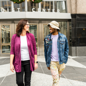 Two people walking out of a building smiling at each other