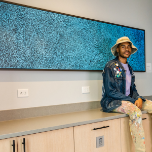 Person sat on a counter top next to a piece of art