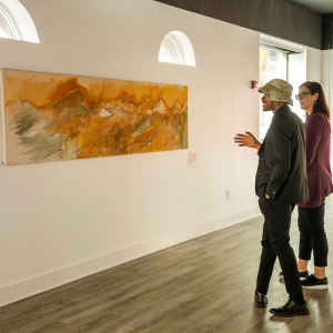 Two people stood up looking at a piece of art on the wall